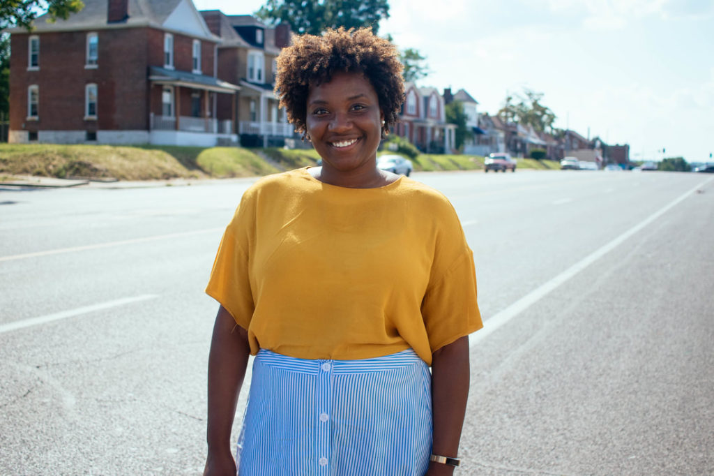 smiling young Black woman standing near city street