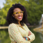 grinning young Black woman with yellow glasses