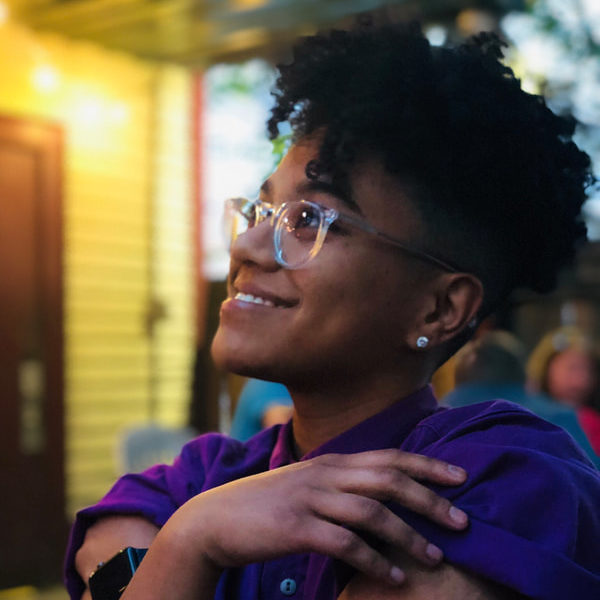 grinning young Black woman with glasses looking to side