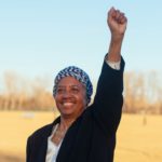 smiling older Black woman with fist in air