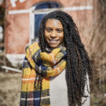 smiling young Black woman with long braids and scarf