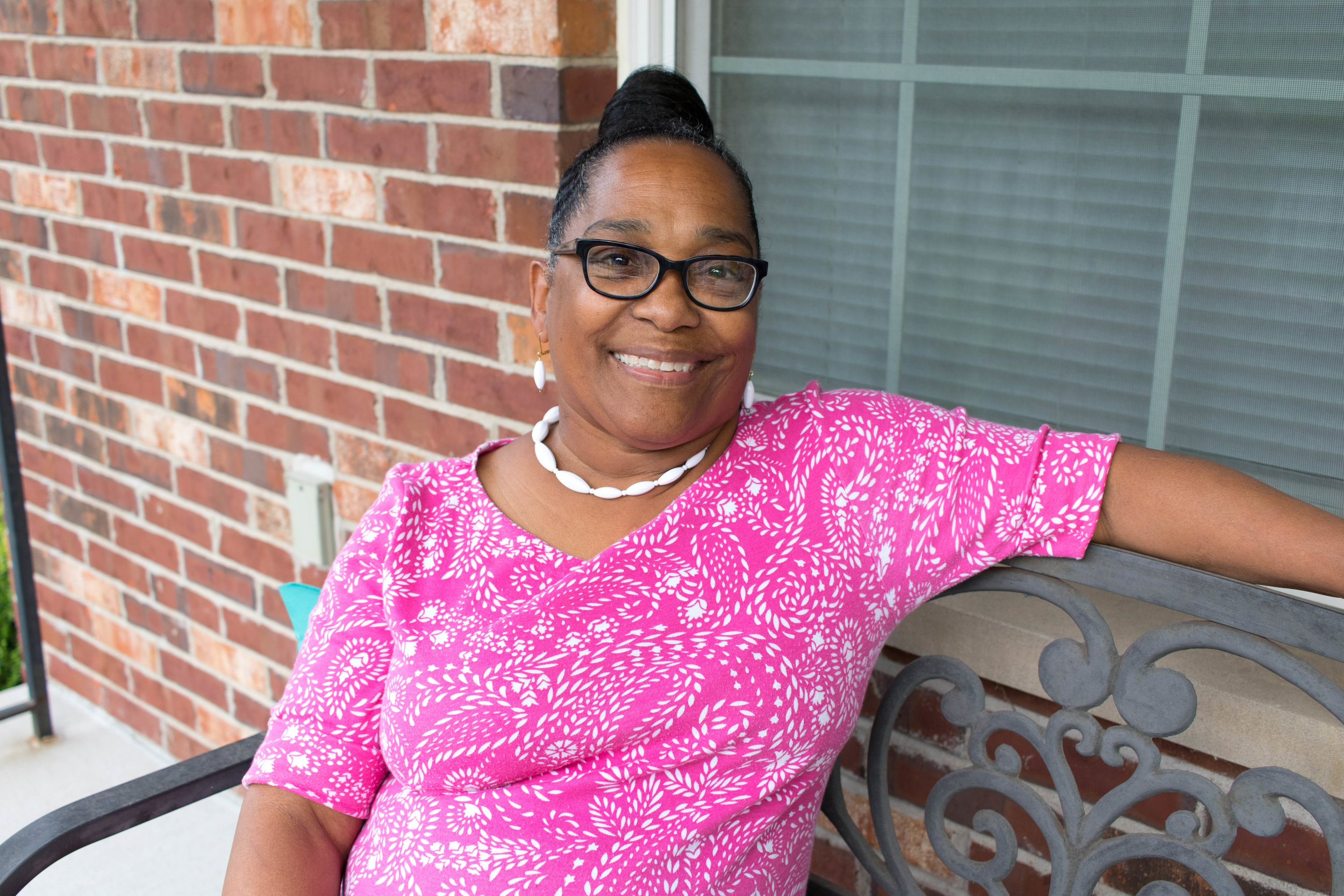 smiling older Black woman with glasses wearing pink dress