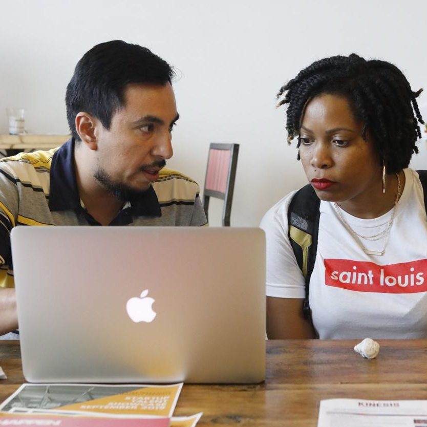 latinx man and black woman looking at laptop