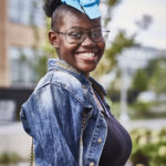 Young smiling Black girl with glasses and hair bow