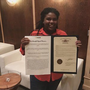 Smiling young black woman holding certificates