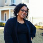 smiling black woman with glasses standing in yard