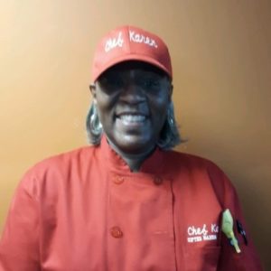 Smiling black woman wearing baseball cap and chef's shirt