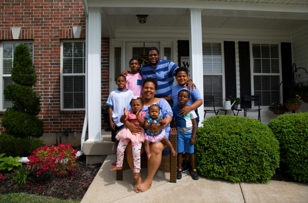 Smiling Black family in front of their home